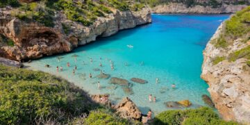 Calo des Moro Beach con agua turquesa cristalina y personas nadando.