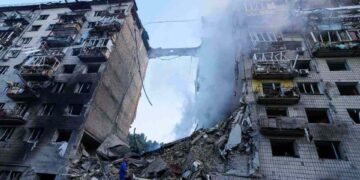 Trabajadores de rescate buscando sobrevivientes en escombros de edificio bombardeado.