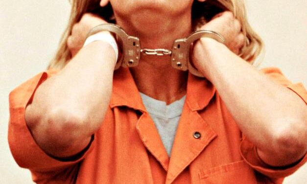 Aileen Wuornos en las esposas, con un mono naranja.