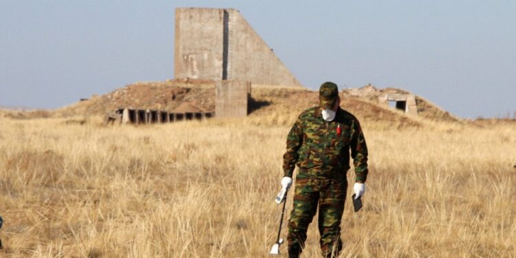 Un hombre con ropa de camuflaje mide los niveles de radiación cerca de los restos de una estructura.
