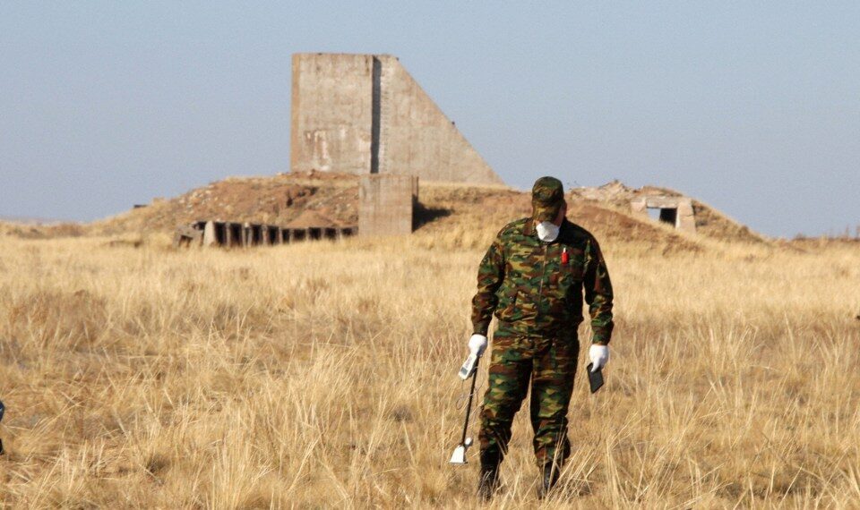 Un hombre con ropa de camuflaje mide los niveles de radiación cerca de los restos de una estructura.