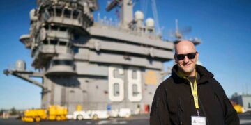 Hombre con gafas de sol de pie en la cubierta de un portaaviones.