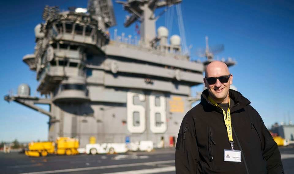 Hombre con gafas de sol de pie en la cubierta de un portaaviones.