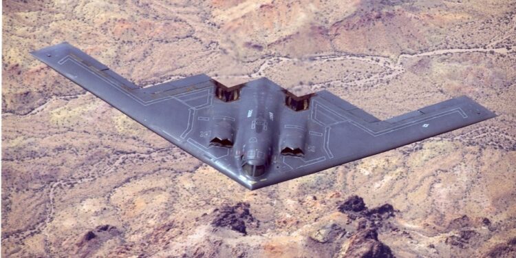 B-2 Bombardero de sigilo espiritual en vuelo sobre el terreno del desierto.
