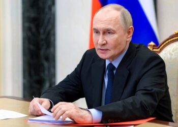 Vladimir Putin revisando documentos en una reunión.