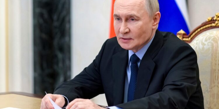 Vladimir Putin revisando documentos en una reunión.