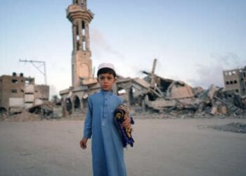 Un niño palestino que lleva su alfombra de oración se posa para una foto antes de unirse a la oración de la mañana Eid al-Adha en Khan Younis en la Franja del Sur de Gaza, el 16 de junio de 2024.
