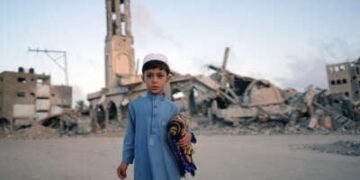 Un niño palestino que lleva su alfombra de oración se posa para una foto antes de unirse a la oración de la mañana Eid al-Adha en Khan Younis en la Franja del Sur de Gaza, el 16 de junio de 2024.