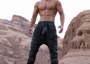 Hombre musculoso de pie sobre una roca.