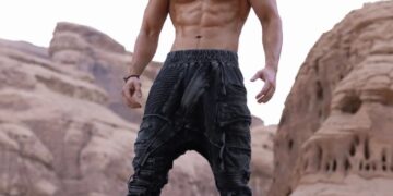 Hombre musculoso de pie sobre una roca.