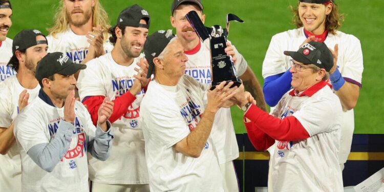 El propietario de los Filis de Filadelfia, John Middleton (R) y el gerente general Dave Dombrowski, levantan el trofeo Warren C. Giles después de que los Filis de Filadelfia derrotaran a los Padres de San Diego en el Juego cinco para ganar la serie de campeonato de la Liga Nacional en Citizens Bank Park en Filadelfia, Pensilvania, el 23 de octubre de 2022. (Michael Rains/Getty Images)
