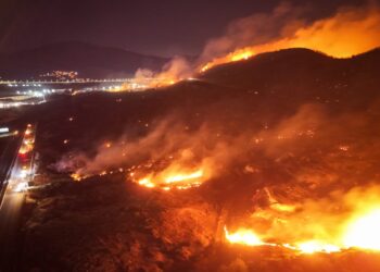 Los bomberos que luchan contra un gran incendio forestal por la noche.