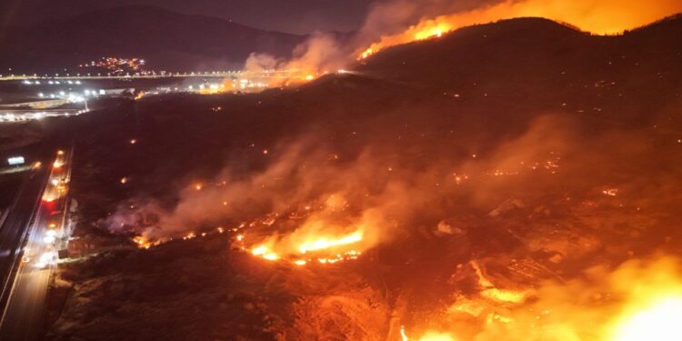 Los bomberos que luchan contra un gran incendio forestal por la noche.
