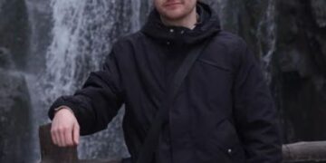 Hombre de pie junto a una cascada.