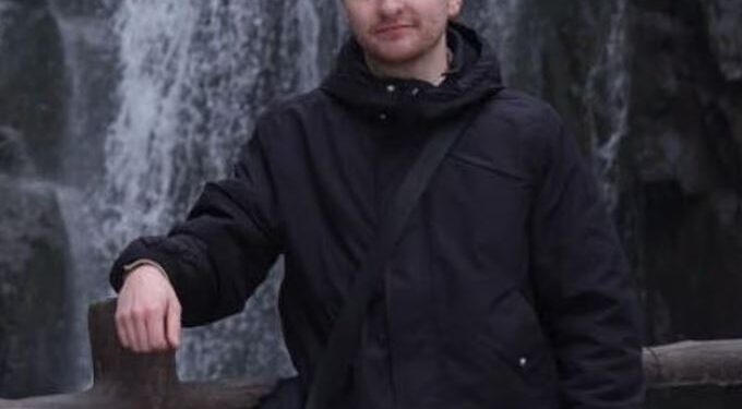 Hombre de pie junto a una cascada.