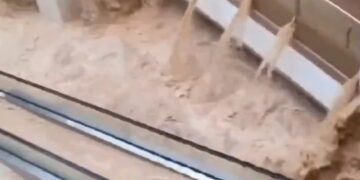 Las aguas de las inundaciones se apresuran a través de un centro comercial, sumergiendo escaleras mecánicas.