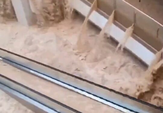 Las aguas de las inundaciones se apresuran a través de un centro comercial, sumergiendo escaleras mecánicas.