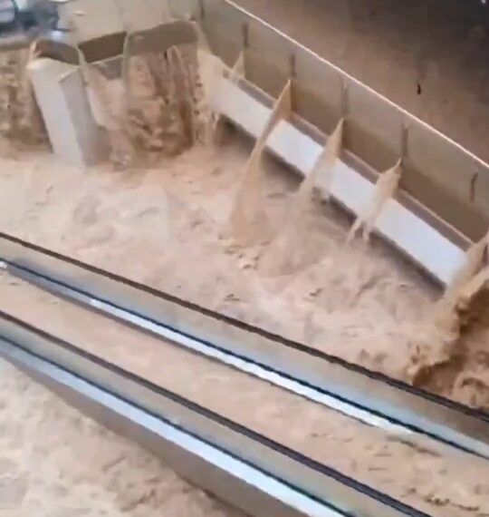 Las aguas de las inundaciones se apresuran a través de un centro comercial, sumergiendo escaleras mecánicas.
