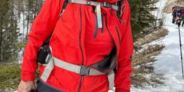 Mujer con chaqueta roja caminando en la nieve.