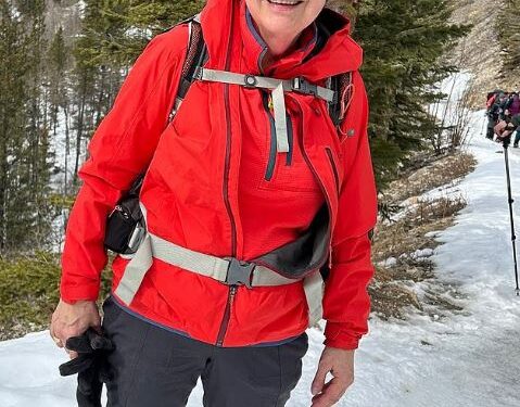 Mujer con chaqueta roja caminando en la nieve.