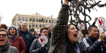 Un estudiante graduado de la Northeastern University aplaude como la congresista Ayanna Pressley (no en la foto) habla con una multitud reunida en apoyo de los estudiantes de trabajadores graduados de la Universidad de Boston que buscan un salario justo, una mejor cobertura de atención médica y beneficios más fuertes, en Boston, Massachusetts, el 26 de marzo de 2024.