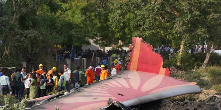 Los escombros de un avión estrellado con gente parada cerca.