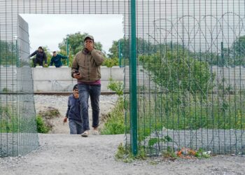 Los migrantes trepan por paredes y cercas cerca de los campos de refugiados.