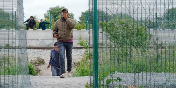 Los migrantes trepan por paredes y cercas cerca de los campos de refugiados.