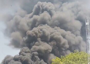 Gran columna de humo negro que ondula sobre los edificios.