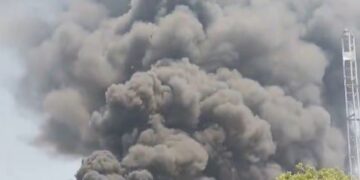 Gran columna de humo negro que ondula sobre los edificios.