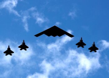 B-2 Spirit Bomber flanqueado por cuatro chorros de combate Raptor F-22.