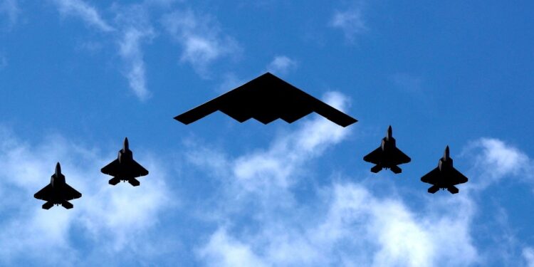 B-2 Spirit Bomber flanqueado por cuatro chorros de combate Raptor F-22.