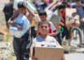 Un niño lleva una caja de suministros de alivio de la Fundación Humanitaria de Gaza (GHF) a medida que los palestinos desplazados regresan de un centro de distribución de ayuda en la Franja Central de Gaza el 29 de mayo de 2025.
