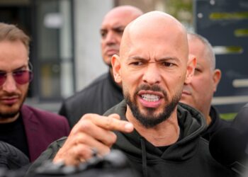 Andrew Tate hablando con los medios de comunicación fuera de una estación de policía.