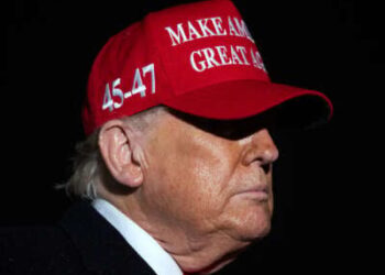 Donald Trump usa un sombrero de maga rojo en la oscuridad