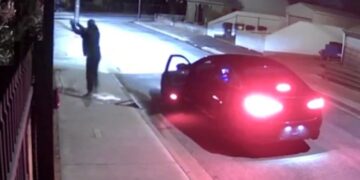 Imágenes de seguridad nocturna de una persona cerca de un automóvil.