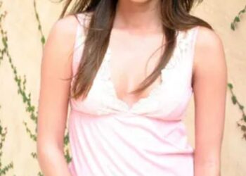 Mujer sonriendo en la camiseta sin mangas rosa y los jeans.