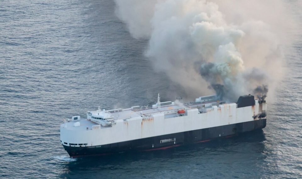 Vista aérea de un barco de carga en llamas en el mar.