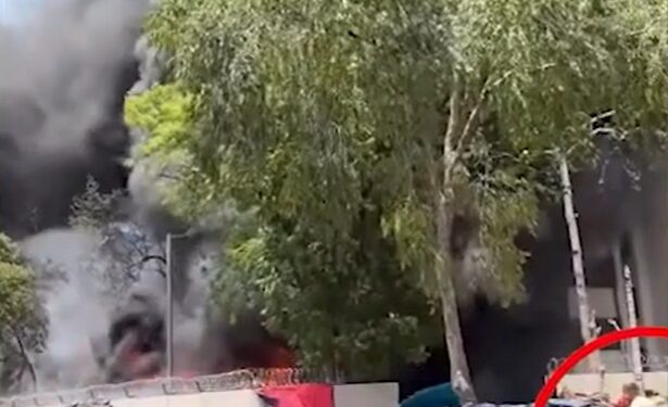 Gran fuego con gente observando desde la distancia.