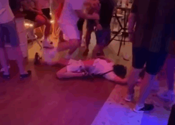 Persona acostada en el piso en un bar lleno de gente.