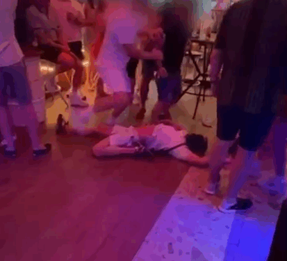 Persona acostada en el piso en un bar lleno de gente.