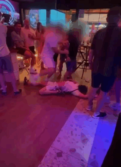 Persona acostada en el piso en un bar lleno de gente.