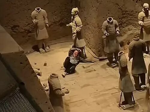 Una persona sentada entre las estatuas del ejército de terracota dañada.