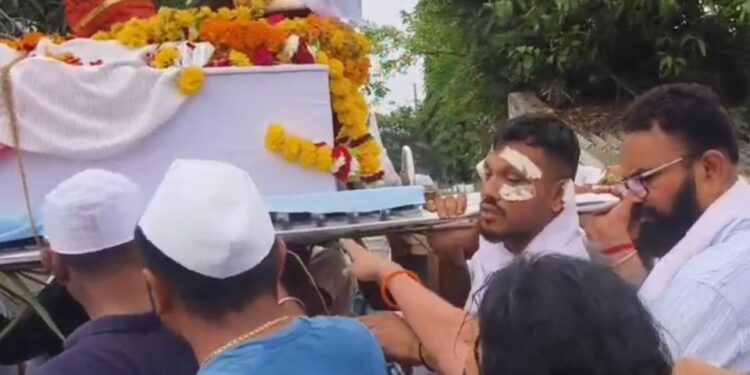 Un hombre que lleva el ataúd de su hermano en una procesión fúnebre.