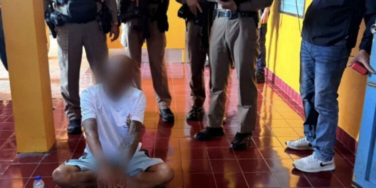 Un monje budista se encuentra en el piso rodeado de agentes de policía.