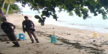 Escena del crimen en una playa con policías.