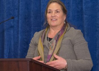 Foto de Joanna Miller hablando en un podio.