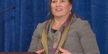 Foto de Joanna Miller hablando en un podio.