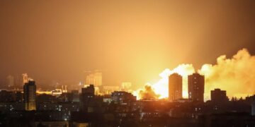 Fuego y humo que se eleva sobre una ciudad por la noche después de una huelga de aviones no tripulados.