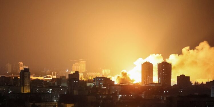 Fuego y humo que se eleva sobre una ciudad por la noche después de una huelga de aviones no tripulados.